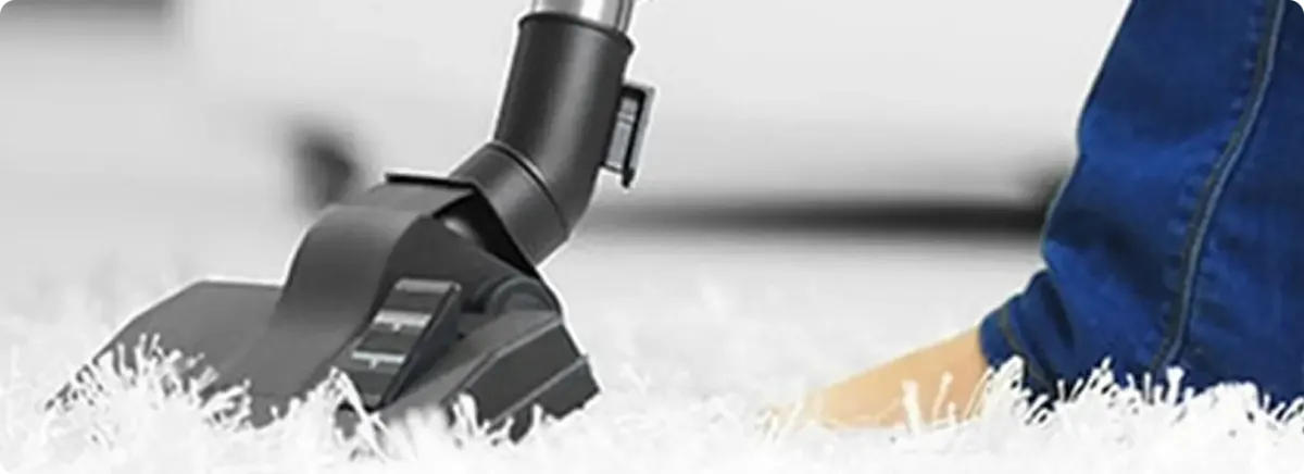 Close-up of a professional vacuuming a white carpet in Woodridge.