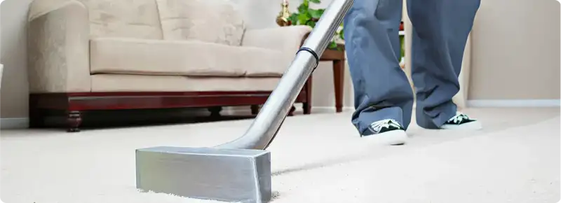 Carpet cleaning technician using a hot-water extraction wand on a light-colored carpet in a living room, Naperville, IL.